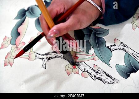 Juye, Juye County. 20th Mar, 2021. A worker draws a peony-themed realistic painting at a painting professional cooperative in Qilin Township, Juye County, Heze City of east China's Shandong Province on March 20, 2021. Heze is noted as one of the key origins of the peony flowers in China. Peony-themed, realistic-style painting as part of the traditional culture in Juye has now become an unique technique for local peasants to increase their income. Credit: Guo Xulei/Xinhua/Alamy Live News Stock Photo