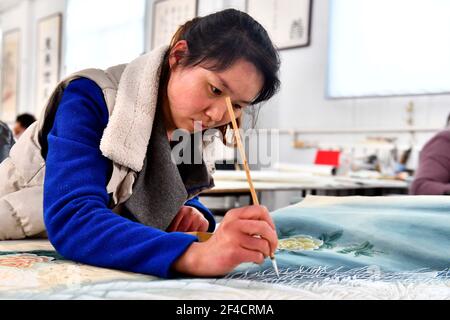 Juye. 20th Mar, 2021. A worker draws a peony-themed realistic painting at the Juye Luxi painting and calligraphy studio in Juye County, Heze City of east China's Shandong Province on March 20, 2021. Heze is noted as one of the key origins of the peony flowers in China. Peony-themed, realistic-style painting as part of the traditional culture in Juye has now become an unique technique for local peasants to increase their income. Credit: Guo Xulei/Xinhua/Alamy Live News Stock Photo