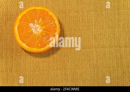 Detail of fresh sliced orange on a rustic canvas fabric texture in yellow woven color Stock Photo
