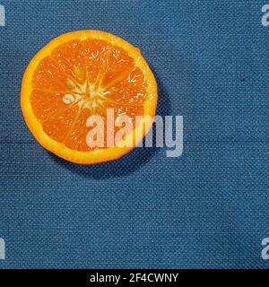 Detail of fresh sliced orange on a rustic canvas fabric texture in blue woven color Stock Photo
