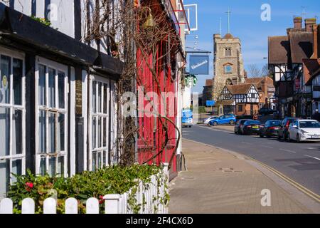 Pinner Village High Street with Carluccios Restaurant & Starbucks on the left & Saint John the Baptist, Medieval hilltop church in the background. Stock Photo