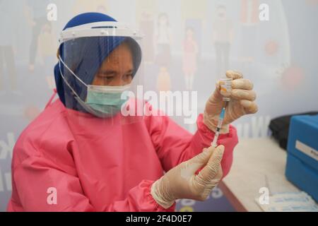 A health worker prepares a dose of Covid-19 vaccine at Kendari City ParkThe mass vaccination program for the elderly was officially implemented on Saturday (20/3/2021) at Kendari City Park. As previously planned by the Kendari City Government, vaccination for the elderly is a priority because the majority of deaths among people with Covid-19 in Kendari City are elderly. The mass vaccination itself will be carried out for one week from March 20 to 27 starting at 8 to 12 o'clock local time. The requirements if you want to get a vaccine injection are also very easy, namely only by bringing a Kend Stock Photo