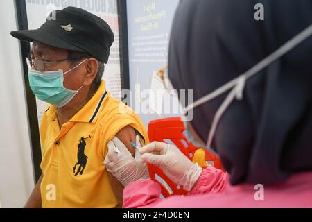 A man wearing a face mask receives the first dose of Covid-19 vaccine.The mass vaccination program for the elderly was officially implemented on Saturday (20/3/2021) at Kendari City Park. As previously planned by the Kendari City Government, vaccination for the elderly is a priority because the majority of deaths among people with Covid-19 in Kendari City are elderly. The mass vaccination itself will be carried out for one week from March 20 to 27 starting at 8 to 12 o'clock local time. The requirements if you want to get a vaccine injection are also very easy, namely only by bringing a Kendar Stock Photo