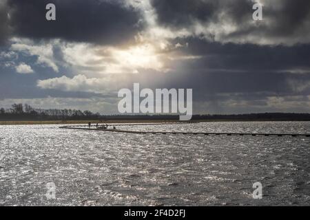 Sun breaking through the dark clouds over the lake in Roegwold, Netherlands Stock Photo