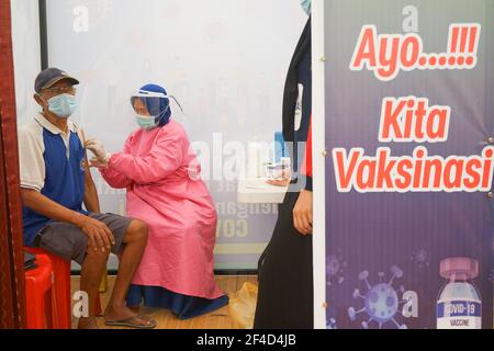 A man wearing a face mask receives the first dose of Covid-19 vaccine.The mass vaccination program for the elderly was officially implemented on Saturday (20/3/2021) at Kendari City Park. As previously planned by the Kendari City Government, vaccination for the elderly is a priority because the majority of deaths among people with Covid-19 in Kendari City are elderly. The mass vaccination itself will be carried out for one week from March 20 to 27 starting at 8 to 12 o'clock local time. The requirements if you want to get a vaccine injection are also very easy, namely only by bringing a Kendar Stock Photo