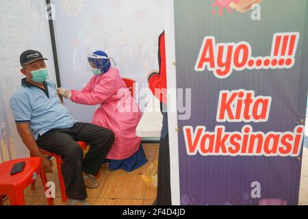 A man wearing a face mask receives the first dose of Covid-19 vaccine.The mass vaccination program for the elderly was officially implemented on Saturday (20/3/2021) at Kendari City Park. As previously planned by the Kendari City Government, vaccination for the elderly is a priority because the majority of deaths among people with Covid-19 in Kendari City are elderly. The mass vaccination itself will be carried out for one week from March 20 to 27 starting at 8 to 12 o'clock local time. The requirements if you want to get a vaccine injection are also very easy, namely only by bringing a Kendar Stock Photo