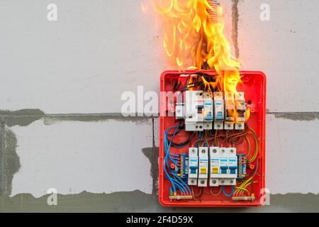 Burning switchboard from overload or short circuit on wall closeup Stock Photo