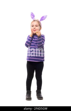 Cute young girl celebrating Easter with bunny ears with anticipation excited expression. Full body isolated on white background Stock Photo