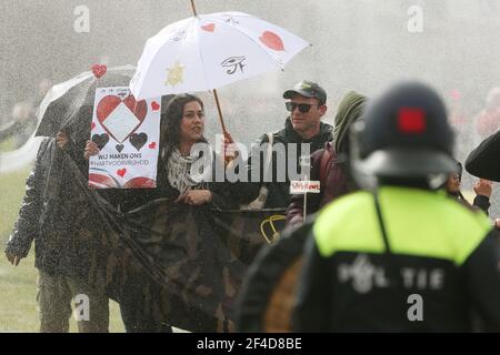 Amsterdam, Netherlands. 20th Mar, 2021. Demonstrators protect themselves with umbrellas from the water sprayed by water cannons. Police on Saturday expelled participants of an unsanctioned protest rally against Corona regulations with water cannons from the central square in front of the Imperial Museum. Credit: David Young/dpa/Alamy Live News Stock Photo