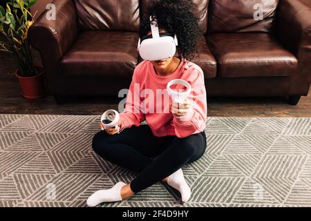 Young woman in casual clothes sitting on the floor in living room Stock Photo