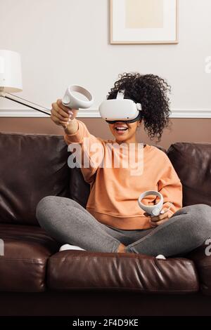 Young cheerful woman relaxing at home using virtual reality headset Stock Photo
