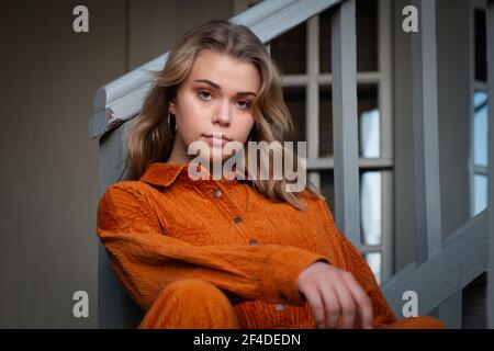 Portrait of a beautiful young woman sitting on a staircase in a hallway Stock Photo