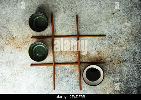 Overhead view of a game of noughts and crosses using Asian chopsticks and bowls Stock Photo