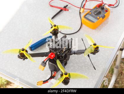 A fpv high-speed racing drone copter and multimeter lying on the table Stock Photo
