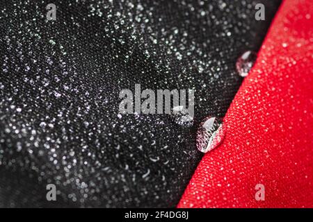 Drops of water on the water-resistant fabric of a waterproof bag of black and red cloth Stock Photo