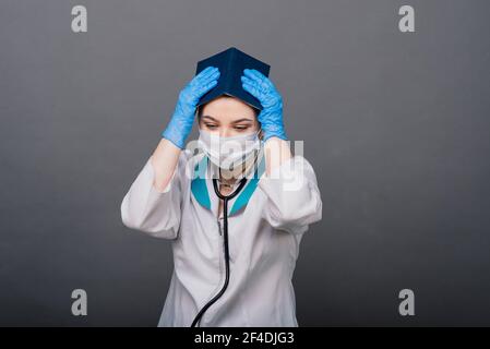Beautiful female doctor holding stethoscope smiling isolated on grey background. Stock Photo