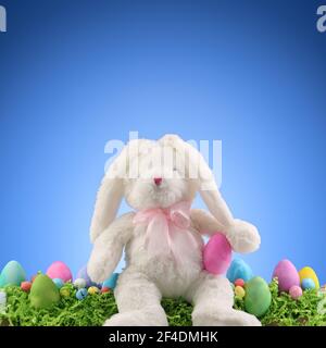 Stuffed animal Easter Bunny surrounded with painted Easter eggs and colorful decorations. Copyspace for text. Stock Photo