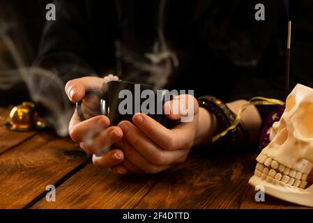 Fortune teller or oracle with holding a black cup for fortune telling on the coffee grounds. Psychic readings and the concept of clairvoyance. Stock Photo