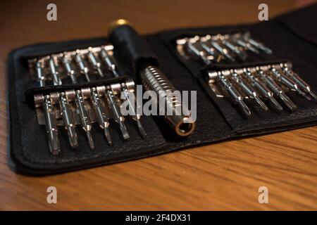 Screwdriver bits made from tool steel in a black leather case isolated on a wooden background Stock Photo