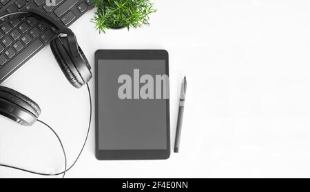 Business workplace with laptop, keyboard, tablet , headphones, pencil and plant. Top view. Copy space. Stock Photo