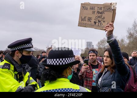 Female protester at an anti lockdown, anti policing bill, protest rally in London, UK, facing off with police officers. We are powerful, message Stock Photo