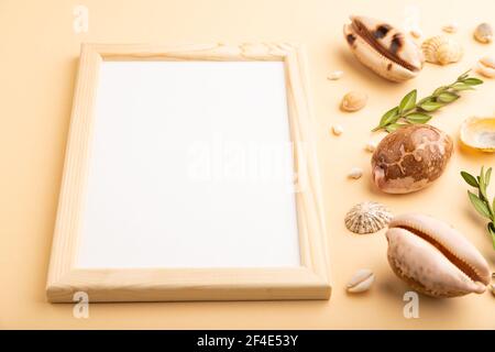 Composition with wooden frame, seashells, green boxwood. mockup on orange background. Blank, side view, still life, copy space. travel concept. Stock Photo
