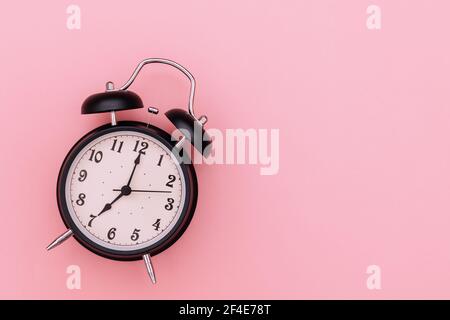 Black alarm clock on pink background Stock Photo