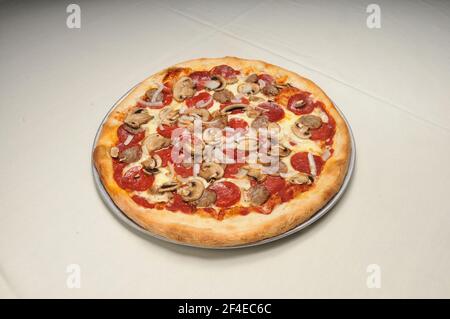 Delicious tomato sauce cheese covered hot and tasty Pepperoni Sausage Mushroom Onion pizza pie Stock Photo
