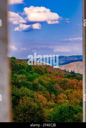 Hillside landscape with clouds in blue sky - Photo framed between walls of houses Stock Photo