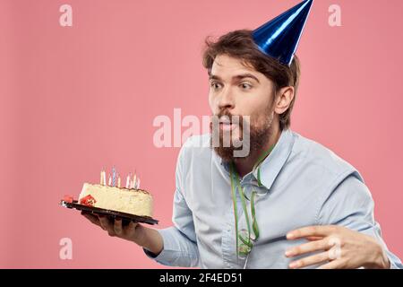 Bearded man with cake tongue on a pink background cropped view and a ...