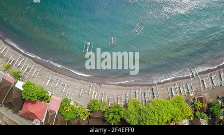 Top down aerial view of traditional Indonesian fishing boats called jukung on black sand beach. In Amed, Bali, Indonesia Stock Photo