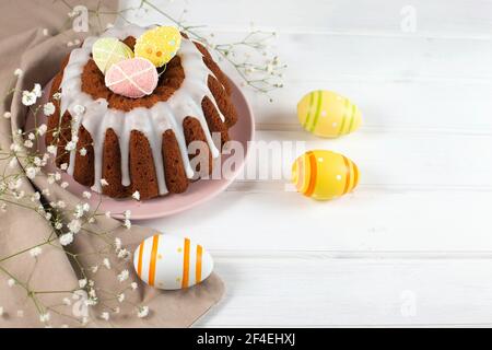Easter cake and colorful eggs on a white wooden background. Sweets for celebrating Easter. Stock Photo
