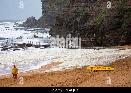 Wild floods in NSW, at Avalon Beach surf rescue volunteer checks the sea foam on the beach,NSW,Australia Stock Photo