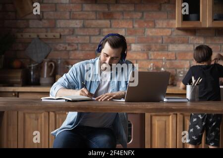 Young Caucasian man make notes working on laptop Stock Photo