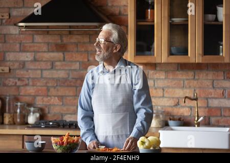 Smiling senior man cooking food in kitchen Stock Photo