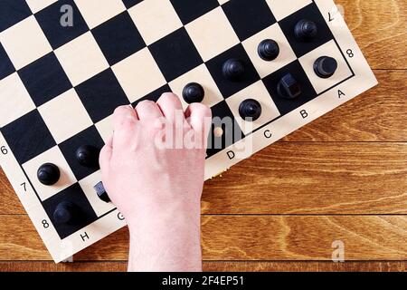 Players hand take a black pawn to do a chess move on the board. Leisure activity and intellectual games Stock Photo