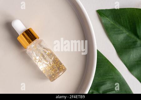 transparent bottle with beauty serum, hyaluronic acid, 24k gold and vitamins on a trayl. Home face and body care concept Stock Photo