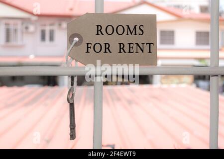 Text on brown paper and key hanging on the window grill with blurred houses Stock Photo