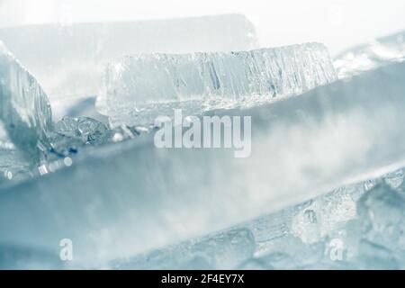 Transparent shining clear ice icicles close-up sparkling on frozen wild lake shore in sunset light. Cold winter nature background Stock Photo