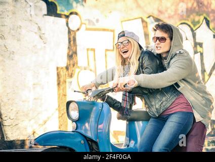 Young couple of lovers haviing fun on a vintage scooter moped - Handsome man in playful attitude with his beautiful girlfriend Stock Photo