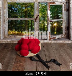 alter Schwarzwälder Bollenhut vor Holzfenster mit Blick in die Landschaft Stock Photo