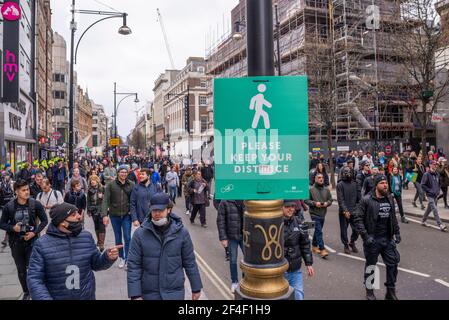 Protesters at a COVID 19 anti lockdown protest march in Westminster, London, UK, passing a social distancing sign which has been altered. Vandalised Stock Photo