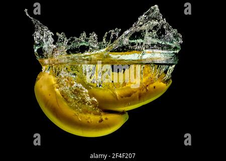 A Bunch Of Bananas Being Dropped Into Water Creating A Vibrant Splash Stock Photo