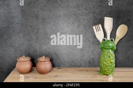 On the kitchen shelf are wooden cooking utensils and dishes. Front view, copy space Stock Photo