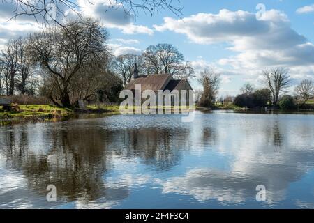 St Leonard's Church in the abandoned Hampshire village of Hartley Mauditt, England, UK, view across the lake Stock Photo