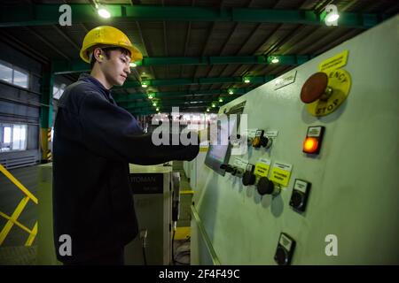 Pavlodar Aluminium electrolysis plant. ingots packing machine. Young Asian operator in yellow hardhat. Stock Photo