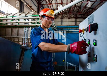 Taldykorgan, Kazakhstan - June 06 2012: Accumulator recycling plant Kainar. Young Asian operator worker and processing line. Stock Photo