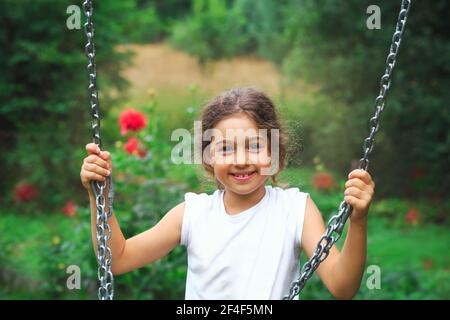 Child playing on outdoor playground. Kids play on school or kindergarten yard. Active kid on colorful swing. Healthy summer activity for children in s Stock Photo