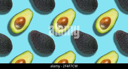 Seamless pattern of fresh green avocado isolated on blue background. Top view Stock Photo