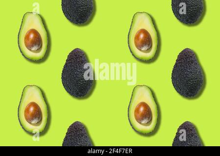 Seamless pattern of avocado halves isolated on green background. Top view Stock Photo